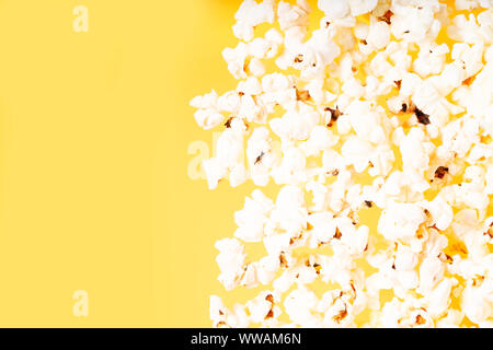 Zerstreut popcorn Grenze über gelbe Schreibtisch Hintergrund Stockfoto