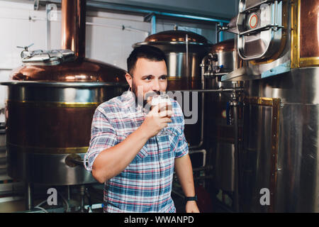 Oktoberfest. Verkostung frisch gebrautes Bier. Brewer hält Glas mit Handwerk Bier. Brauerei Konzept. Mann mit Bier in der Tasse. Alkohol. Männliche Brauer hält Stockfoto