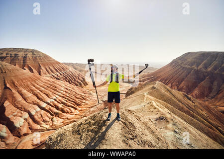 Der bärtige Mann mit zwei Kameras auf der Spitze des Berges in der Wüste Stockfoto