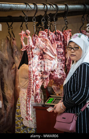 Xian, China - Juli 2019: Frau kaufen Schaf und Kuh Tierkörperfleisch vom Street Food Anbieter Shop im muslimischen Viertel von Xian Stadt muslimische, Shaanxi Stockfoto