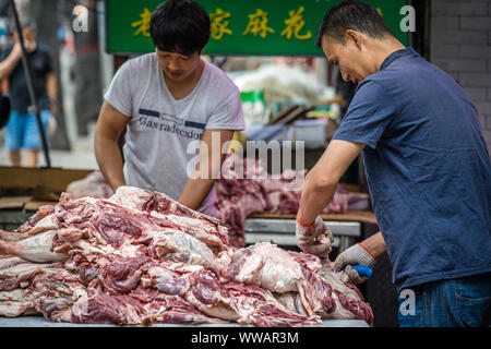 Xian, China - Juli 2019: Zwei Männer Arbeiter schneiden und die Trennung von Lamm und Rind Karkasse Fleisch und Knochen, die Street Food Anbietern im muslimischen Viertel Stockfoto