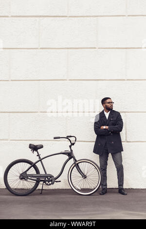 Junge afrikanische Mann mit Fahrrad stehend über weiße Wand Stockfoto