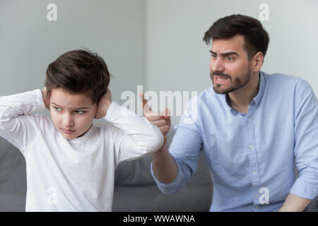 Wütende Vater schrie hartnäckige pingelig kleinen Sohn schließen Ohren Stockfoto