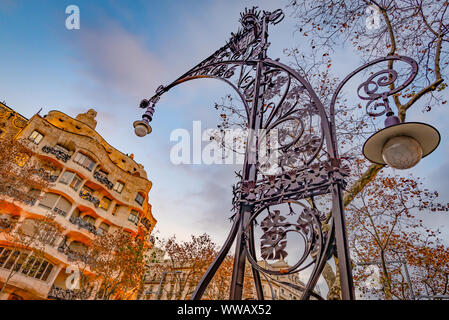 Weitwinkelaufnahme eines kunstvollen Licht Post mit Casa Mila (La Pedrera) im Hintergrund, Barcelona, Spanien Stockfoto