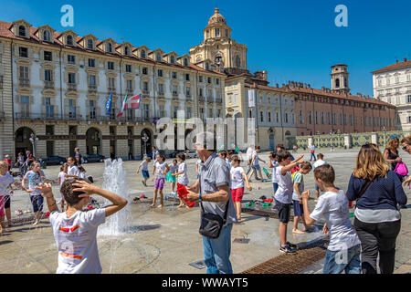 Kinder spielen an einem heißen Sommertag in Turin, Italien, in den Springbrunnen auf der Piazza Castello, einem prominenten Stadtplatz Stockfoto