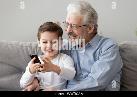Happy senior Großvater und mittels Smart Phone zu Hause Enkel Stockfoto