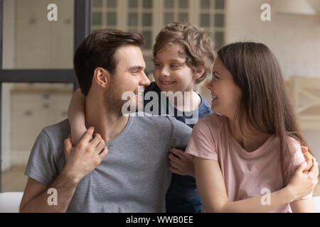 Süße kleine Vorschule junge umfasst zwei lächelnde liebevolle Eltern. Stockfoto