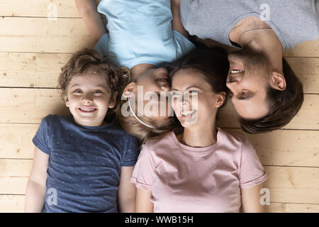 Top oben sehen frohe Familie liegen auf beheizten warmen Boden. Stockfoto