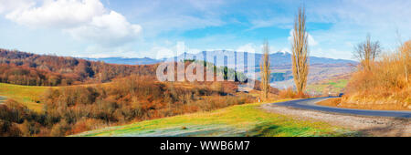 Sonnigen morgen in bergiger Landschaft. Panorama der Ukrainischen Karpaten ländlichen Gegend im November. blattlosen Bäume auf Hügeln und entlang der Straße biegen. Ri Stockfoto