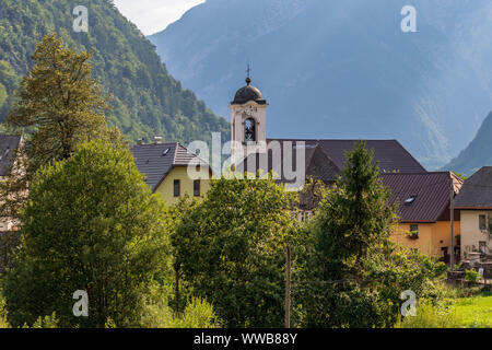 Panorama mit Gebäuden, und die Pfarrkirche in der Bergwelt des Dorfes Log pod Mangartom. Bovec, Slowenien, Europa. Stockfoto