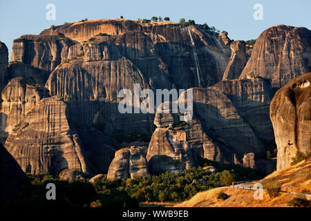 Meteora, die Agios Nikolaos (Sankt Nikolaus) Anapafsas entfernt Kloster lookin, so klein vor dem riesigen Felsen. Trikala, Thessalien, Griechenland. Stockfoto