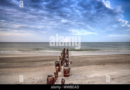 Mond über eine alte Pier im Meer bei Port Royal Beach bei Sonnenaufgang in Naples, Florida Stockfoto