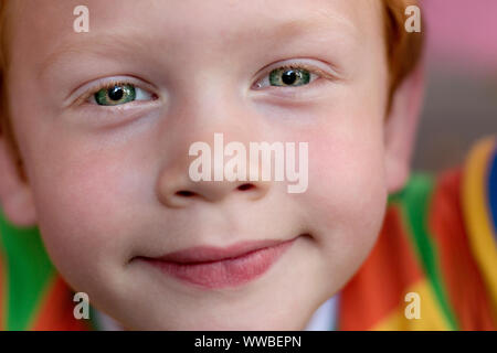 Nahaufnahme der schöne junge Augen. Portrait Kind mit grünen Augen direkt in die Kamera. Lustige kleine Kind mit Ingwer lockiges Haar. Vision Stockfoto