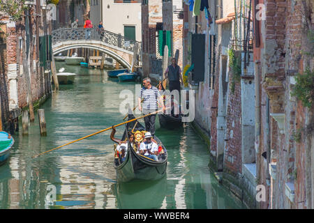 Venedig, Italien, 20. April 2019: Kanal mit Gondeln und historische Häuser eng, in einer schönen, sonnigen Tag. Stockfoto