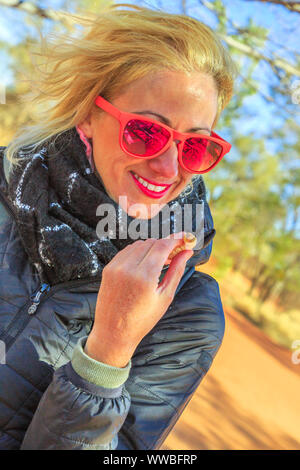 Touristische Frau mit einem Witchetty Maden, die Feeds auf den Wurzeln der witchetty Bush Common in Northern Territory, Australien. Der grub war das Essen Stockfoto