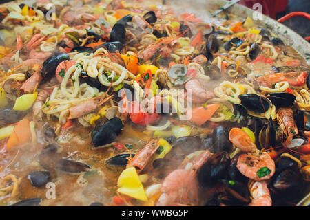 Paella mit Meeresfrüchten ist in eine große Kapazität gekocht. Große Stockfoto