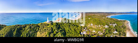 Weißer Stein Byron Bay Leuchtturm an der Spitze der grüne Wald bedeckt Landspitze in weiten Antenne Byron Bay Panorama mit Blick auf Stadt und Küste mit Stränden u Stockfoto