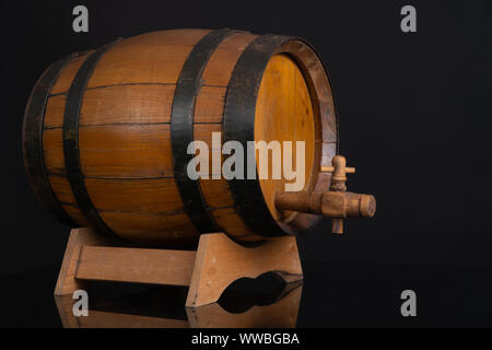 Holzfass mit Tippen auf einem schwarzen Spiegel. Schwarzer Hintergrund hinter.. Stockfoto