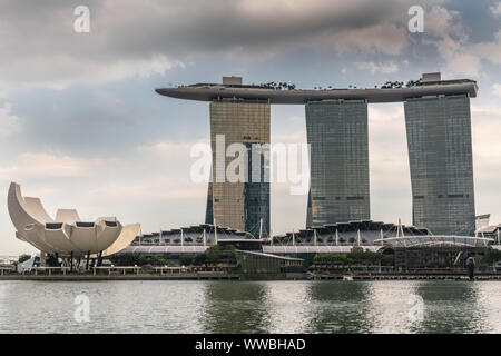 Singapur - März 20, 2019: Marina Bay Sands Hotel und Casino mit seinen drei Türmen von hinter der Bucht unter Öffnung cloudscape gesehen. Weißes Oberteil ist Kunst - Stockfoto