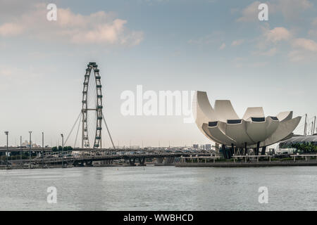 Singapur - März 20, 2019: Riesenrad, der Flyer, und Shell oder Lotus wie weiße Stein ArtScience Museum zwischen Himmel öffnen und Mari erfasst Stockfoto