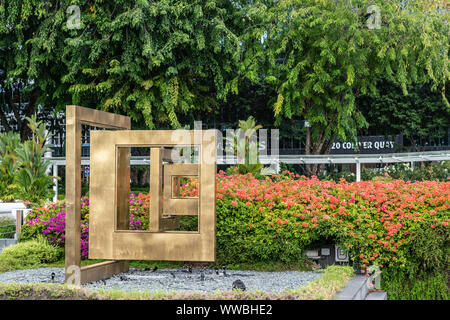 Singapur - März 20, 2019: Gold farbigen Fenster der Hoffnung Statue auf Collyer Quay unter roten Blüten und Laub. Stockfoto