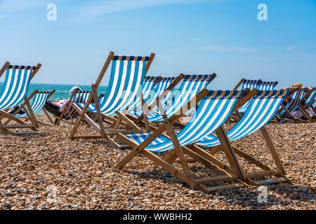 Liegestühle am Strand von Brighton an einem sonnigen Tag Stockfoto