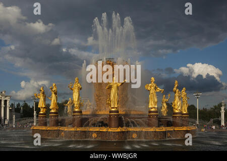 Die Freundschaft der Nationen (Freundschaft der Völker) Brunnen auf dem Hauptplatz im Messegelände VDNH (Ausstellung der Errungenschaften der Volkswirtschaft) in Moskau, Russland. Der Brunnen wurde von sowjetischen Architekten Konstantin Topuridze mit 16 vergoldeten Statuen der Nationen der Sowjetunion durch sowjetischen Bildhauer Zinaida Bazehenova, Alexey Teneta, Iosif Chaykov, Zoya Ryleyeva und andere in 1954 gebaut wurde eingerichtet. Der Brunnen ist auch bekannt als die Goldene Garbe. Stockfoto