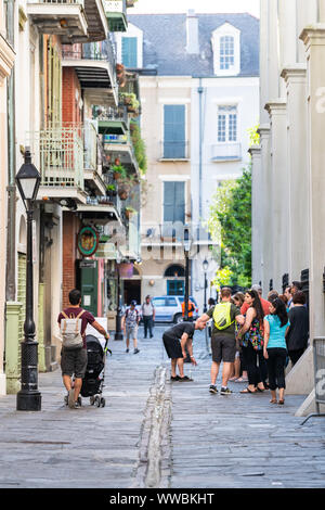 New Orleans, USA - 23. April 2018: Altstadt Straße in Louisiana Stadt mit vielen Menschen zu Fuß auf dem Bürgersteig durch die Gebäudewand mit Führung Gruppe und Stockfoto