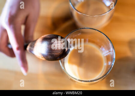 Flache Oberseite Detailansicht von zwei Gläser mit fermentierten traditionelle japanische Reis Drink von Amazake auf Küche Holztisch mit Frau hand Holz la Stockfoto