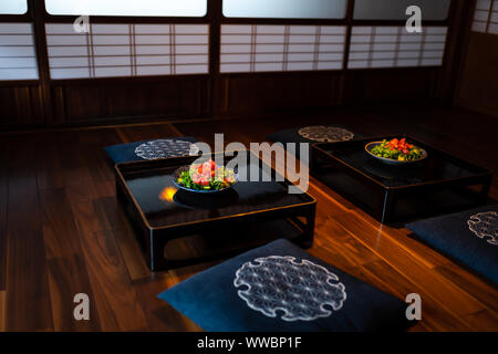 Traditionelle japanische Haus oder Ryokan restaurant Zimmer mit zwei Salat Teller am Tisch, Kissen Kissen mit Shoji Schiebetüren Türen Papier im Hintergrund Stockfoto