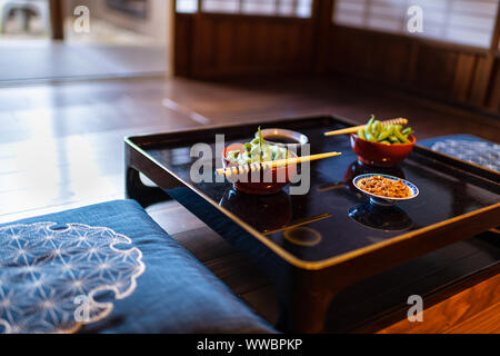 Traditionelle japanische Restaurant Ryokan kaiseki mit gemüsegericht gekochte Salz edamame, natto und Soja Sauce auf dem Teller von Stäbchen mit Shoji slidi Stockfoto