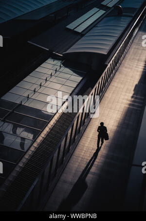 Blick von oben auf eine Person im Schatten, die auf einem sonnendurchfluteten Gehweg in Osaka, Japan, läuft Stockfoto