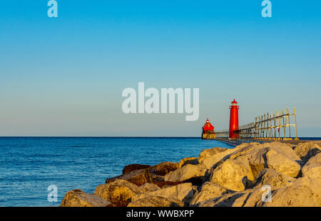 Das goldene Sonnenlicht eines Sommermorgens leuchtet auf dem roten Leuchtturm am Lake Michigan in Grand Haven, Michigan. Stockfoto