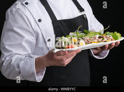 Koch in Uniform dient ein Gericht in einer Platte Stockfoto