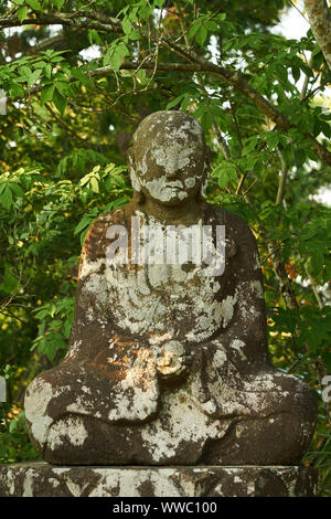 Buddhistische Gottheit in Stein gemeißelt und von Grün auf Oshima Island in Matsushima, Miyagi, Japan umgeben. Stockfoto