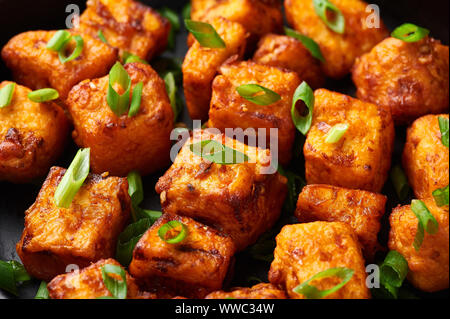 Paneer Mandschurischen oder Paneer 65 in der Schüssel am Schwarzen konkreten Hintergrund. Paneer mandschurischen ist indische, chinesische Küche Teller mit panner Käse, Tomaten, auf Stockfoto