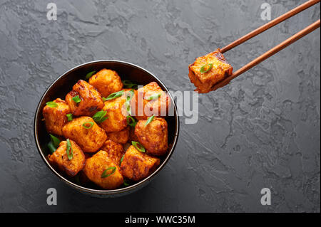 Paneer Mandschurischen oder Paneer 65 in der Schüssel am Schwarzen konkreten Hintergrund. Paneer mandschurischen ist indische, chinesische Küche Teller mit panner Käse, Tomaten, auf Stockfoto