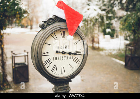 Outdoor Konzept der frohe weihnachten urlaub Eve altes Eisen Uhr mit Titel und Santa rot weißen Hut auf es auf Schnee Straße von New York Stockfoto