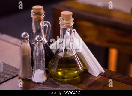 Flaschen mit Olivenöl, Balsamico-Essig, Salz und Pfeffer Shaker auf Tisch im Restaurant. Stockfoto