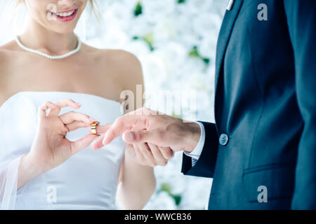 7/8-Ansicht von lächelnden Braut die Hochzeit Ring am Finger Stockfoto