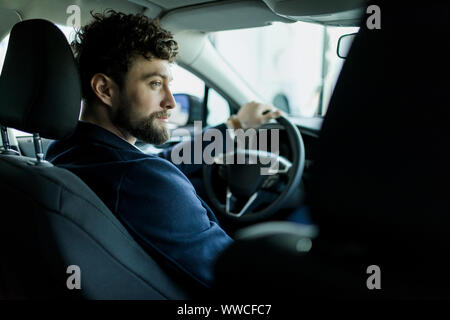 Rückansicht des Menschen in einem neuen Auto sitzen im Showroom. Stockfoto