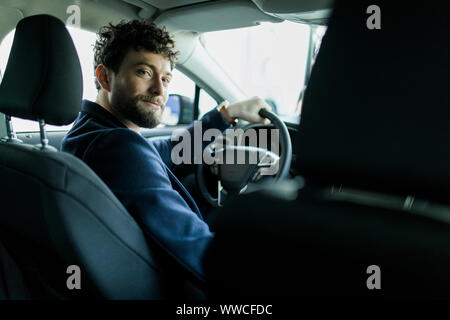 Rückansicht des Menschen in einem neuen Auto sitzen im Showroom. Stockfoto