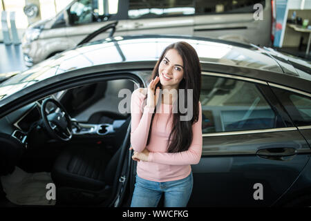 Schöne junge Frau kauft ein Auto im Autohaus Limousine. Stockfoto