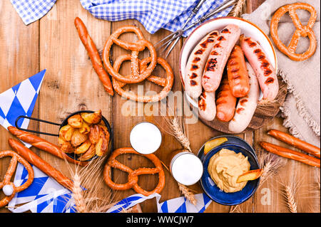 Traditionelle deutsche Würstchen und Gebäck für das Bierfest. Zwei Gläser Bier. Holz Hintergrund und Dekor. Ansicht von oben Stockfoto