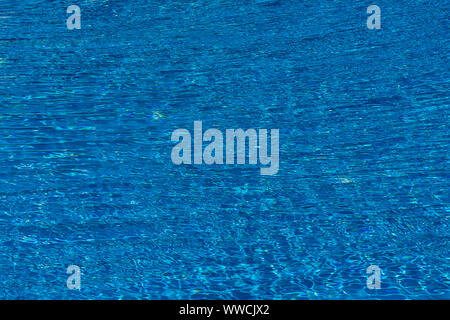 Wasser Wellen auf blau gefliesten Pool Hintergrund. Blau Türkis Pool Wasser. Wellen von der Sonne beleuchtet. Fliesen sichtbar unten. Ansicht von oben Stockfoto