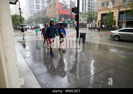 Touristen und Menschen zu Fuß durch die sintflutartigen Regenfälle auf dem Bürgersteig in der Innenstadt von Chicago Illinois USA fallen Stockfoto