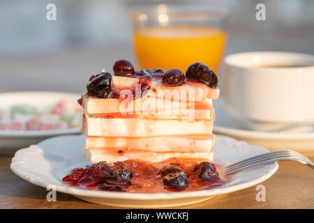 Quark mit roter Kirsche Marmelade, Orangensaft und eine Tasse Kaffee auf den Tisch. Frühstück Konzept. Nahaufnahme Stockfoto