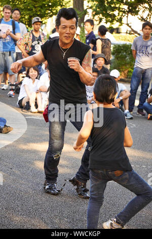 Ein Mann und ein Junge von The Strangers, einem Tokyo Rockabilly Club, tanzen an einem sonnigen Sommersonntagnachmittag im Yoyogi Park in Shibuya, Tokio, Japan. Stockfoto