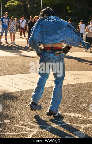 Ein japanisches Mitglied von The Strangers, einem Tokyo Rockabilly Club, tanzt im Yoyogi Park an einem sonnigen Sommersonntagnachmittag in einer Jeansjacke. Stockfoto