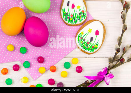 Ostern Hintergrund mit Ostereiern und eine Weide Zweig. Ostern Lebkuchen, Eier und Weide Zweig auf weißem Holz- Hintergrund. Ostern Trend Farben Stockfoto
